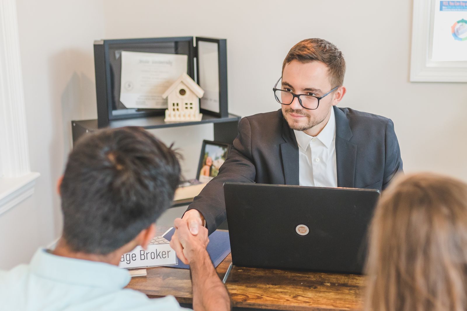 A friendly mortgage broker shaking hands with happy clients